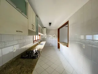 Vista da cozinha com armários brancos e piso de cerâmica.