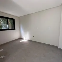Foto de um cômodo interno com paredes brancas e piso cinza.