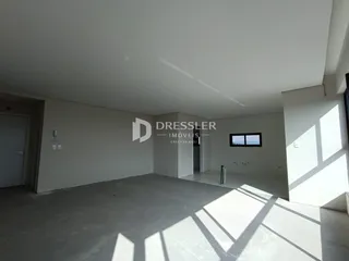 Imagem de um ambiente interno com paredes brancas e piso de concreto.