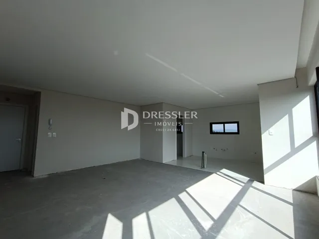 Imagem de um ambiente interno com paredes brancas e piso de concreto.