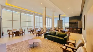 Sala de estar com grandes janelas e área de jantar em um apartamento.