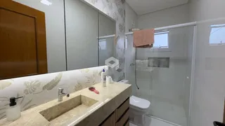 Vista da área de banheiro com bancada e box de vidro.