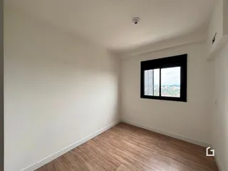 Ambiente interno de uma sala com piso de madeira e janela.