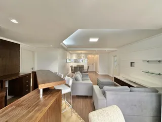 Sala de estar moderna com sofá cinza e piso de madeira clara.