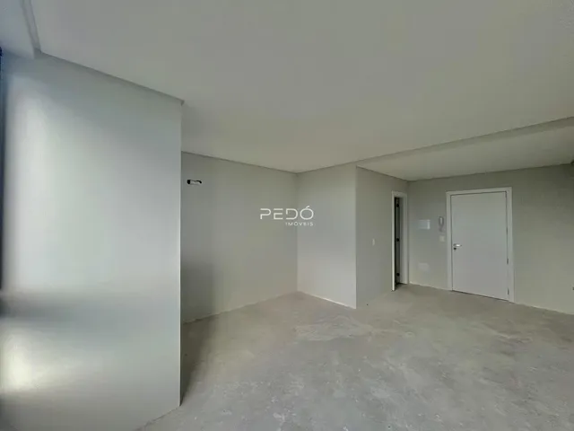 Interior de um cômodo com piso de concreto cru e paredes brancas.