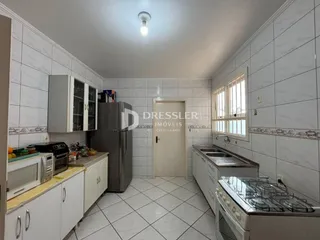 Foto de uma cozinha com armários brancos e piso cerâmico.