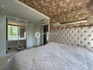 Quarto com cabeceira estofada e papel de parede floral na parede.