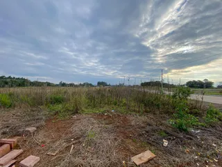 Vista de uma área externa com vegetação seca e solo exposto.