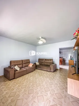 Sala de estar com dois sofás marrons e piso de cerâmica claro.