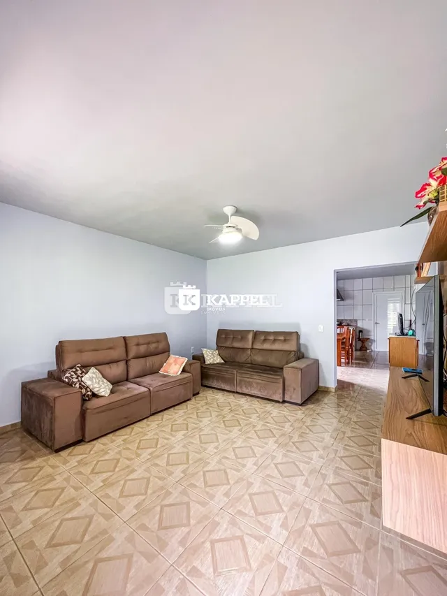 Sala de estar com dois sofás marrons e piso de cerâmica claro.