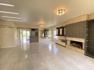 Sala de estar ampla com piso claro e parede de lareira.