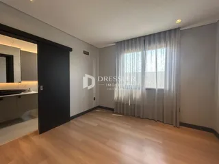 Sala de estar com piso de madeira clara e janela com cortinas transparentes.