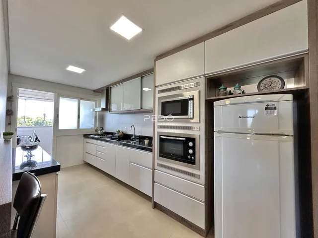 Vista da cozinha moderna com armários brancos e eletrodomésticos em Lajeado.