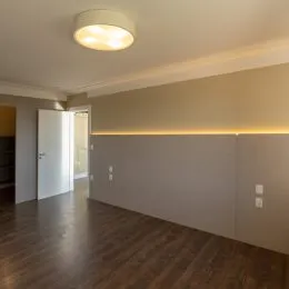 Hall de entrada com piso de madeira e iluminação embutida nas paredes.