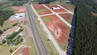 Vista aérea de um terreno com áreas de terra e vegetação ao longo de uma estrada.