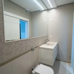 Foto de um banheiro interno com revestimento de parede e louças brancas.