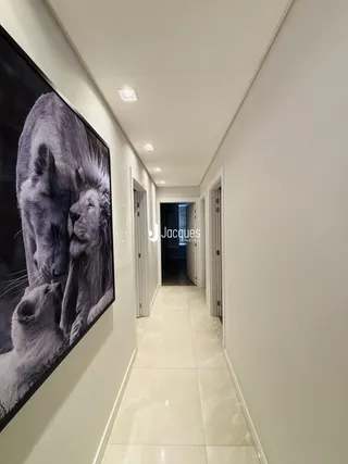 Corredor interno de uma residência com piso claro e paredes brancas.