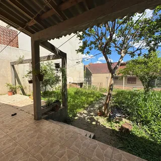Vista externa de um quintal com vegetação e estrutura de madeira.