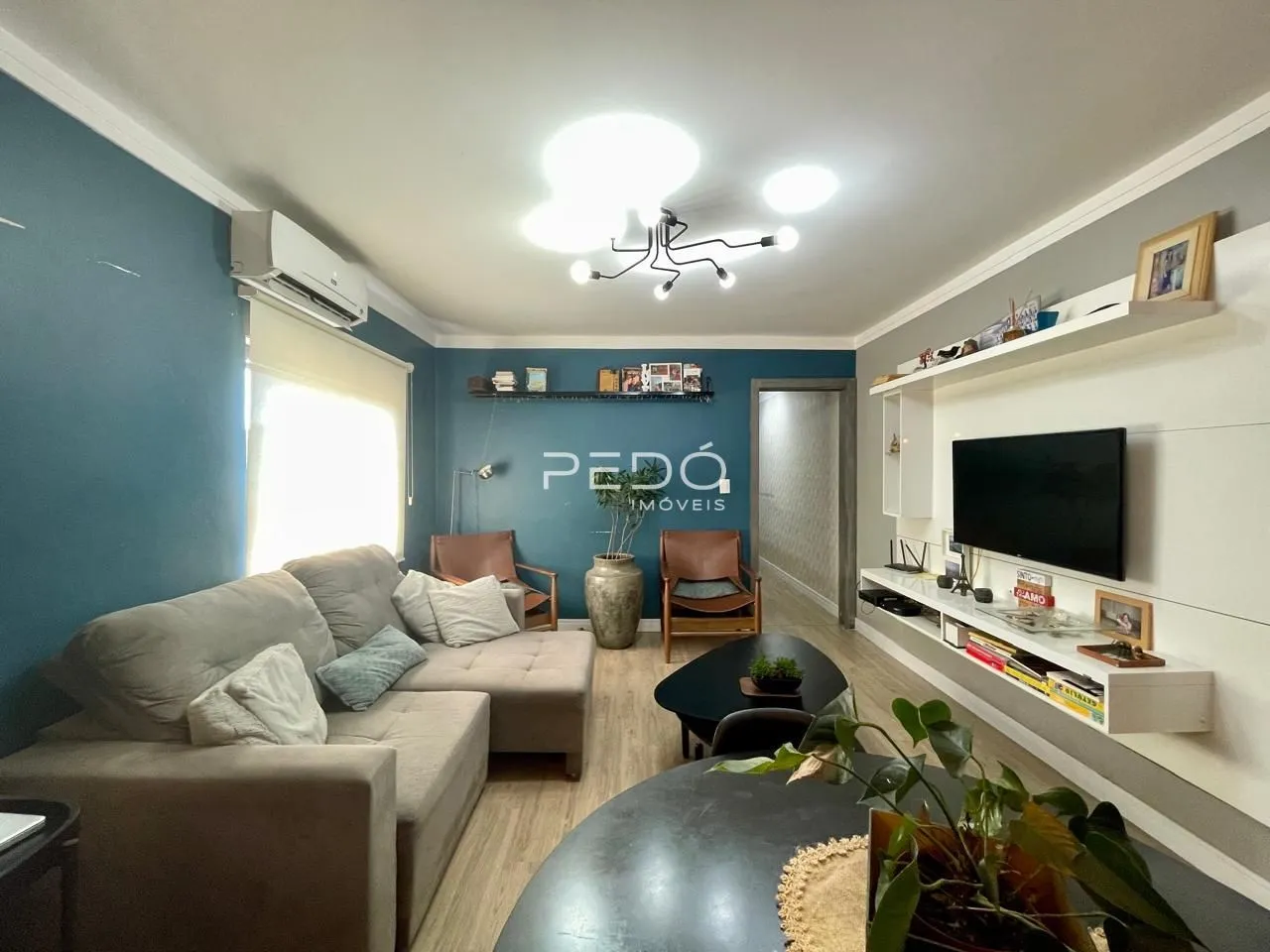 Sala de estar com sofá e painel de TV em um apartamento no Brasil.