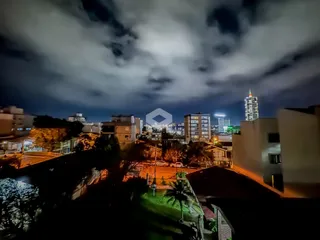 Vista noturna de um bairro em Lajeado, Brasil, com edifícios ao fundo.