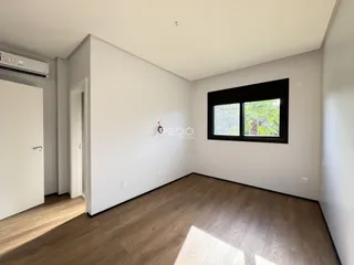 Ambiente interno de uma sala com piso de madeira e janela.