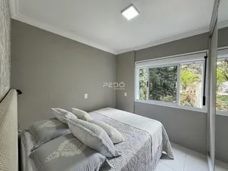 Quarto com cama e janela de vista para a natureza.
