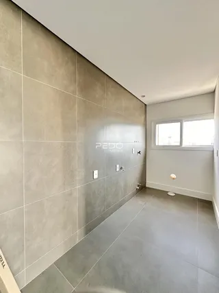 Hall de corredor com revestimento de cerâmica clara nas paredes e no piso.