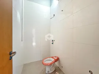 Hall de banheiro com paredes brancas e piso de concreto na propriedade.