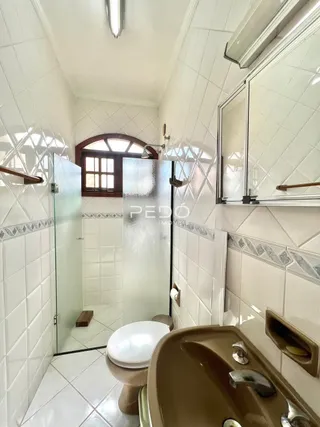 Foto de um banheiro com revestimento cerâmico e box de vidro.