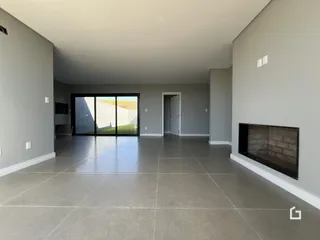 Sala ampla com piso de cerâmica e porta de vidro que dá para a paisagem.