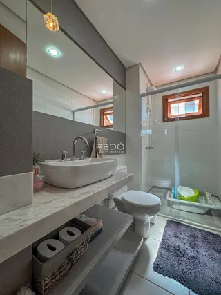 Foto de um banheiro moderno com bancada de mármore e box de vidro.