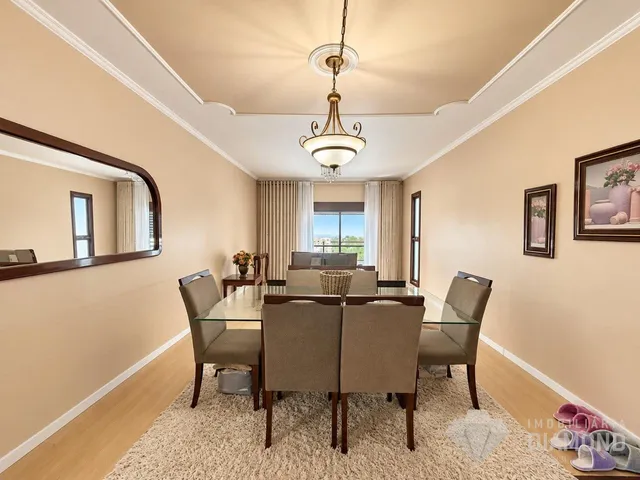 Uma sala de jantar com mesa de vidro e cadeiras em um imóvel.