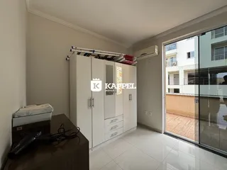 Quarto com armários brancos e vista para o exterior através de uma porta de vidro.