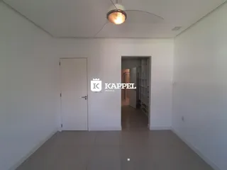 Hall de entrada com paredes brancas e piso claro.
