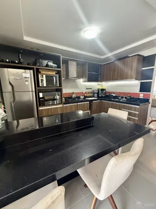 Vista da cozinha moderna com armários escuros e bancada preta.