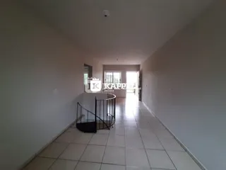 Corredor interno com piso de cerâmica e escadaria metálica.