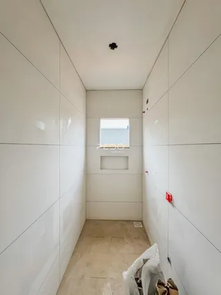 Corredor interno de um imóvel em Lajeado, Brasil, com paredes brancas e piso em construção.