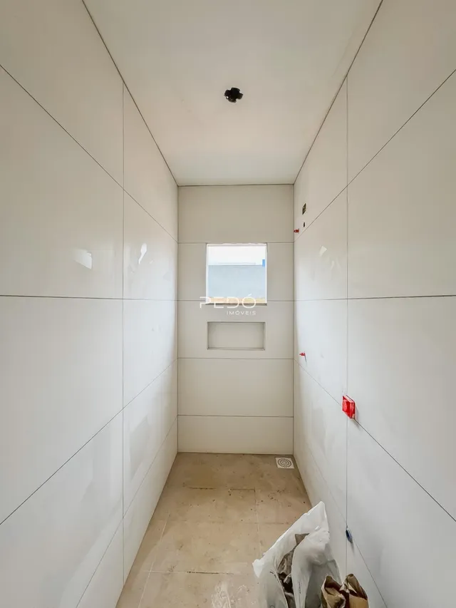 Corredor interno de um imóvel em Lajeado, Brasil, com paredes brancas e piso em construção.