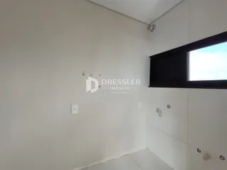 Vista interna de um corredor com paredes brancas e piso claro.