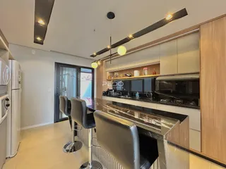 Vista interna de uma cozinha moderna com armários de madeira e bancadas escuras.