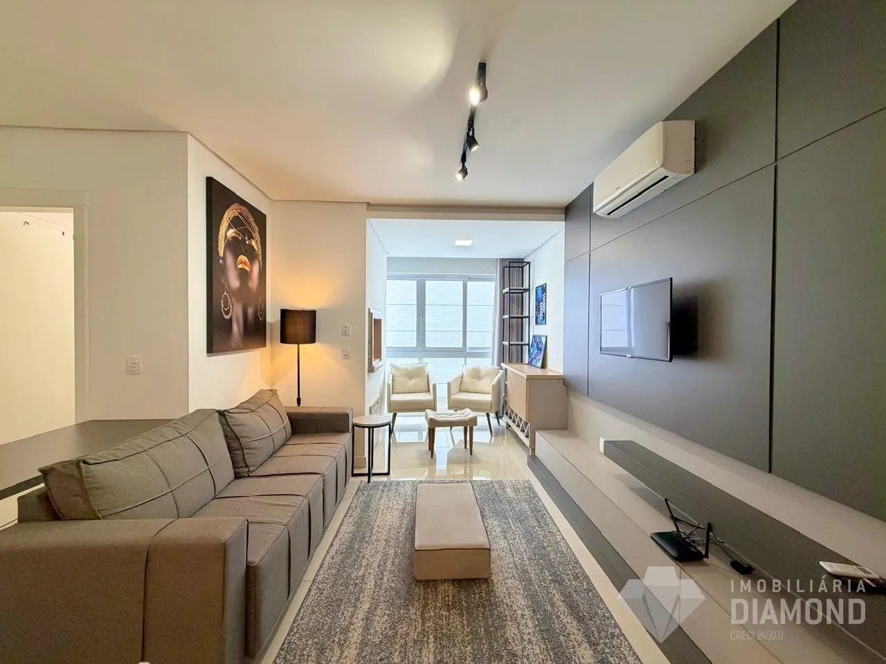Sala de estar com sofá e televisão montada na parede.