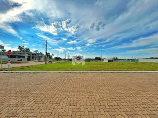 Vista externa de um terreno com piso de tijolos e gramado.