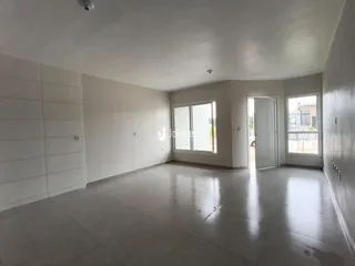Interior de uma sala ampla com paredes brancas e piso claro.