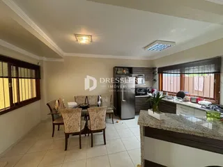 A sala de estar apresenta janelas de madeira e um ambiente interno claro.