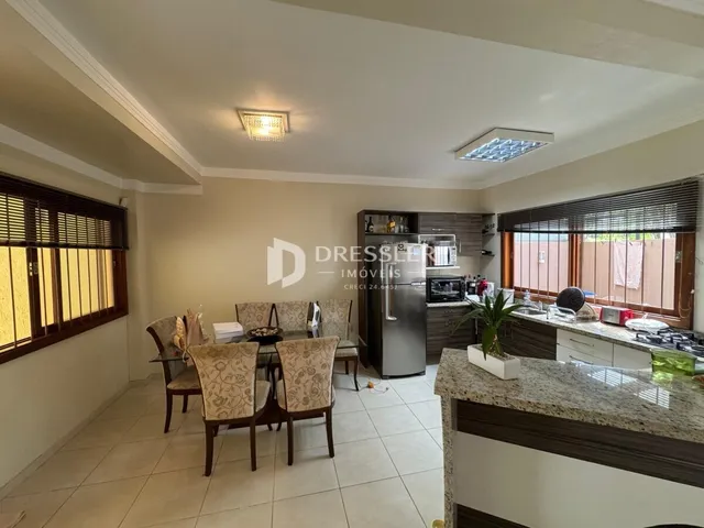 A sala de estar apresenta janelas de madeira e um ambiente interno claro.