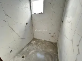 Foto de um corredor interno com paredes brancas e piso claro.