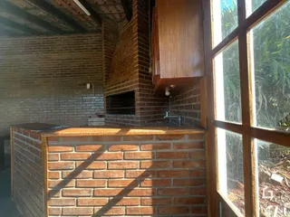 Interior com paredes de tijolo aparente e janela com vista para a vegetação externa.