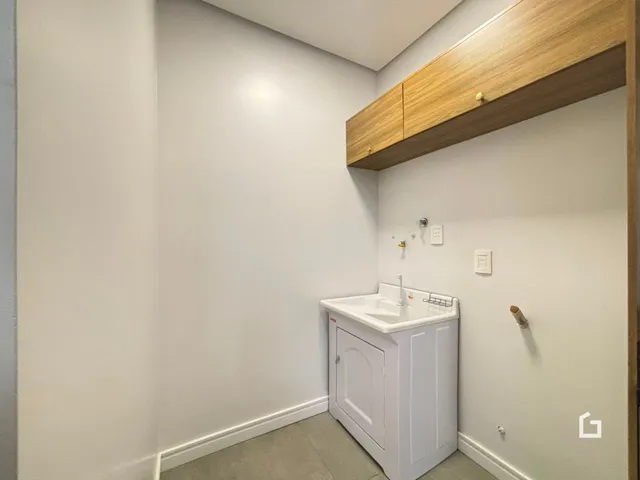 Foto de um banheiro com bancada branca e armário branco.
