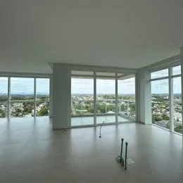 Vista ampla de um espaço interno com grandes janelas que oferecem uma paisagem urbana.