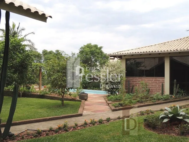 Vista da fachada de uma propriedade com jardim e caminho de tijolos.